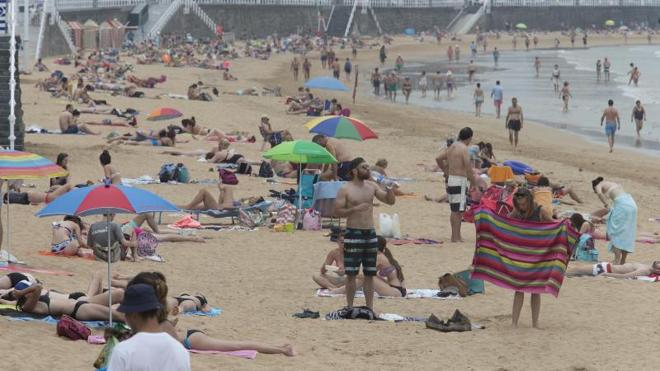 La playa de San Lorenzo, en Gijón, ha vuelto a ser este lunes el lugar elegido por miles de personas para sobrellevar las altas temperaturas. 