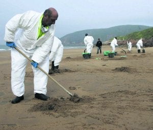 Los operarios de Tragsa recogen el fuel en la playa de Xivares. ::
PALOMA UCHA