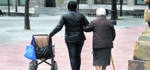 Una mujer, usuaria de silla de ruedas y que necesita bastón para caminar, pasea acompañada por un familiar. ::                             MARIO ROJAS