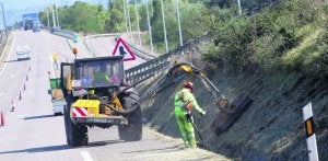 Una brigada maneja la desbrozadora mecánica y la manual para despejar los márgenes en la carretera que lleva al polígono de Silvota. ::                             PABLO NOSTI