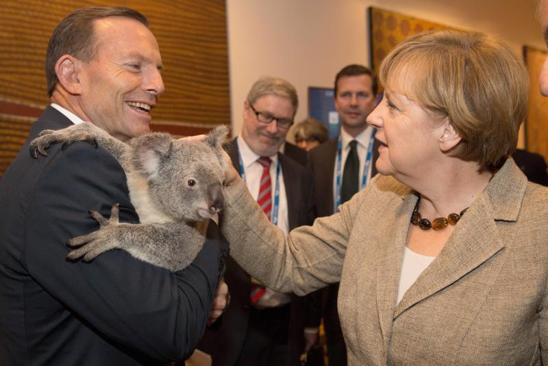 La canciller alemana Angela Merkel acaricia al koala, que sujeta Abbott.