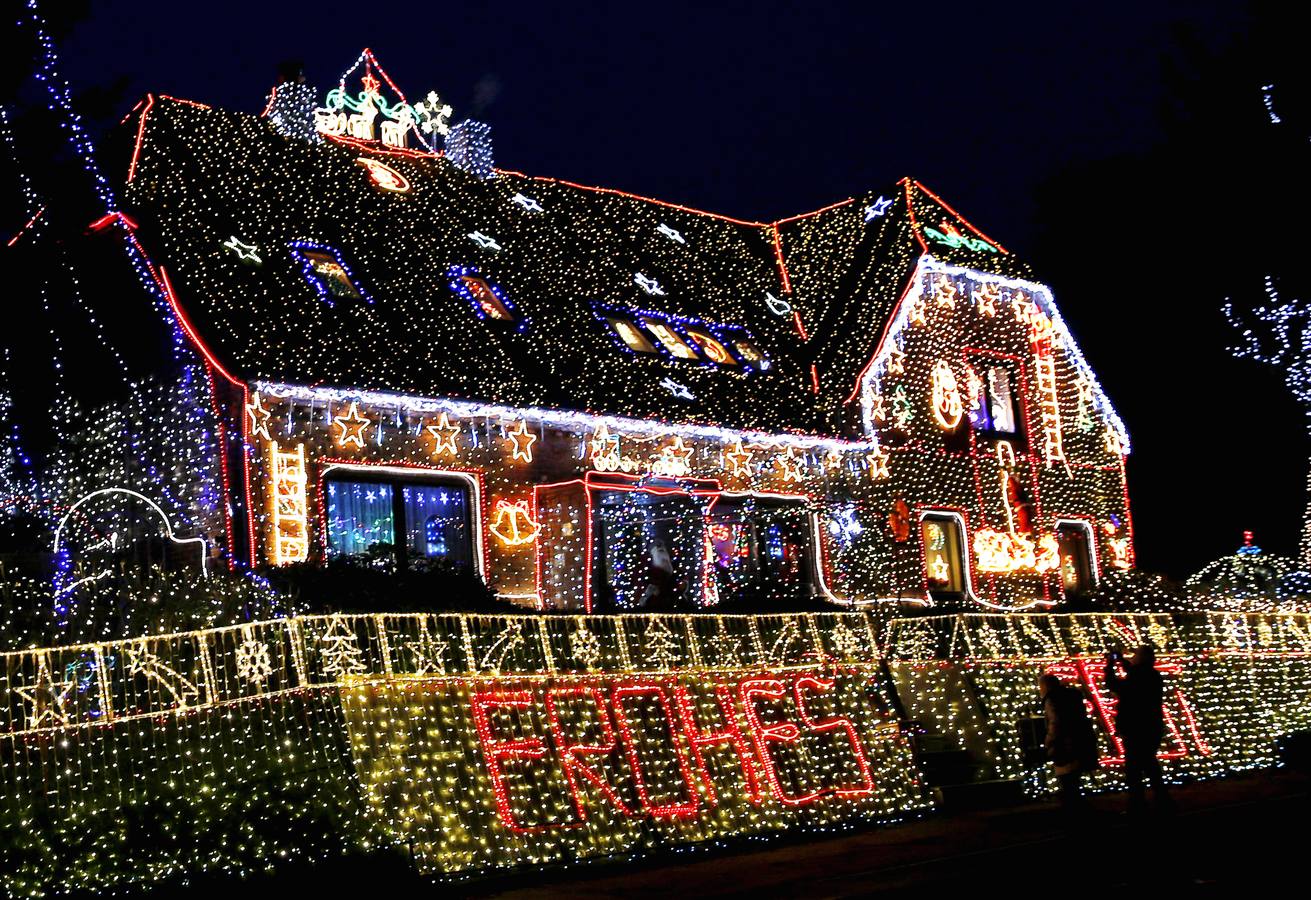 Juego de Luces en Bremen. Un grupo de turistas saca fotos de una casa decorada con la señal 'Frohes Fest' (Feliz Navidad) en Bremen, al sur de Alemania, el 2 diciembre. Ralf Vogt, el dueño de 66 años de la casa apodada como 'Lichterhaus' (casa de luces) empezó a poner la decoración a principios de marzo. Encender las 450.000 bombillas del tendido le cuesta 2.500 euros por las cuatro semanas de diciembre. Vogt empezó a decorar su casa después de visitar los Estados Unidos en el año 2000.