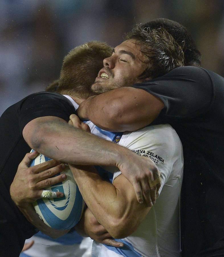 Abrazo de delanteros, los neozelandeses Richie McCaw y Charlie Faumuina (125 kilos) sujetan al medio de apertura argentino Juan Martín Hernández.