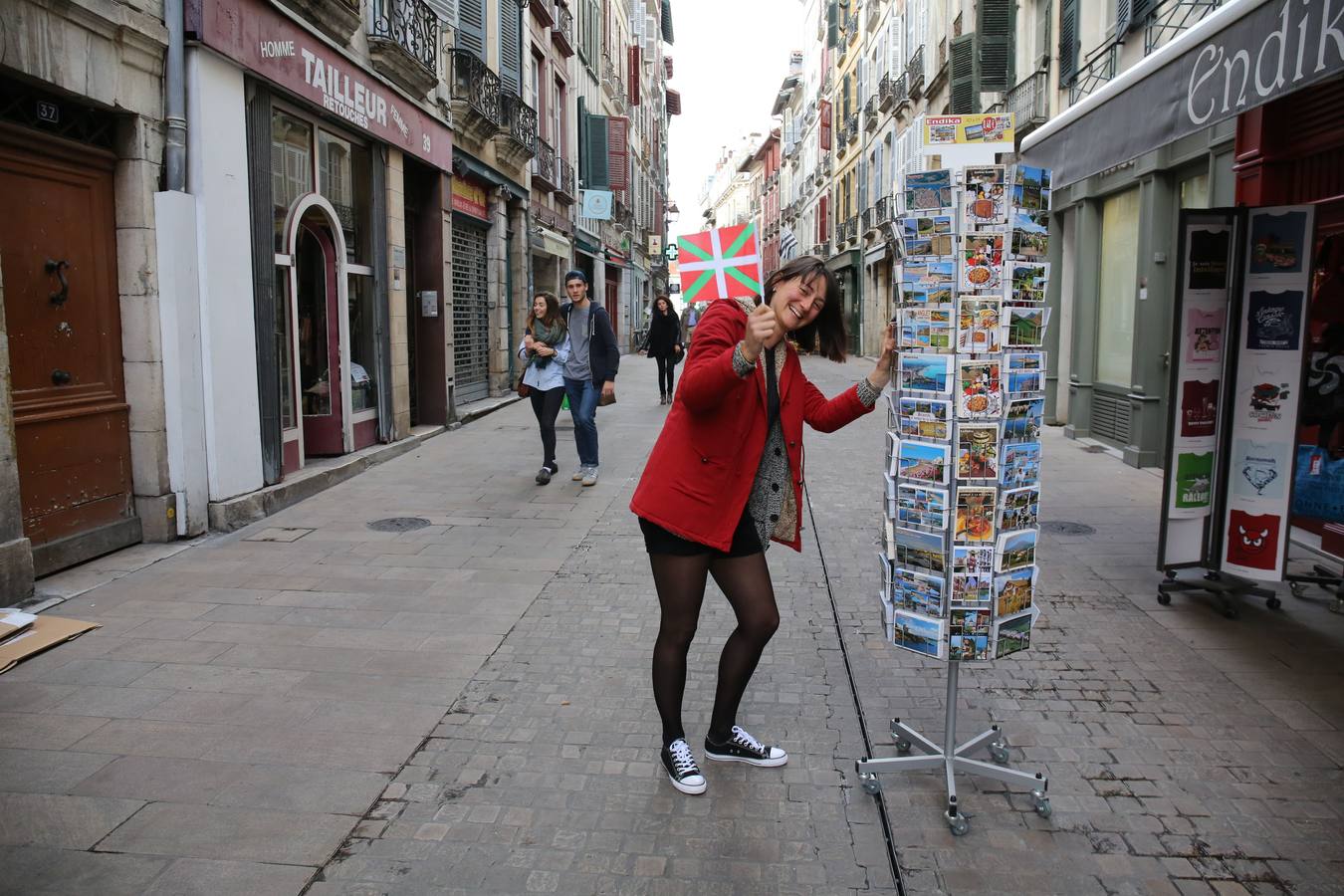 Marion Veunac sonríe con una ikurriña en la mano junto a su tienda de souvenirs en Bayona.