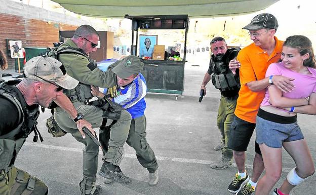 Simulación. Los instructores, antiguos miembros de unidades especiales del Ejército hebreo, repelen un simulacro de agresión con cuchillo junto a dos de sus clientes.