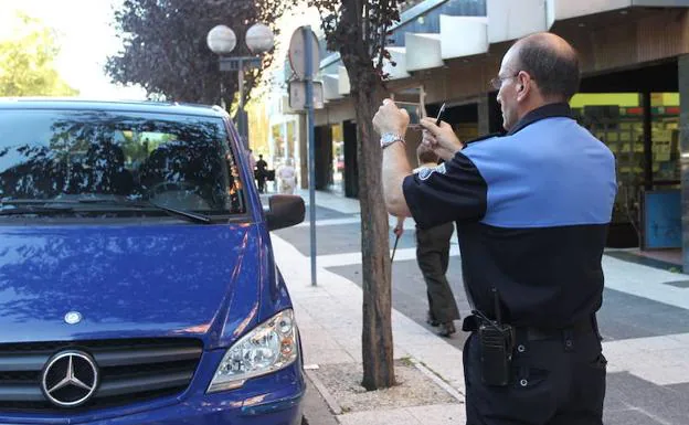 Un agente de la OTA fotografía un vehículo en la calle Gorbea de Vitoria. 