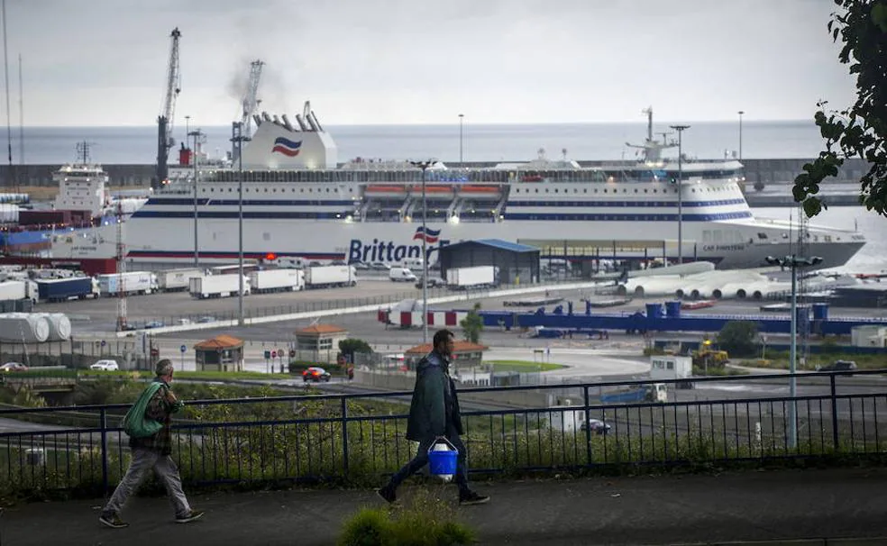 Dos inmigrantes, en la linde del puerto, con el ferry de fondo.