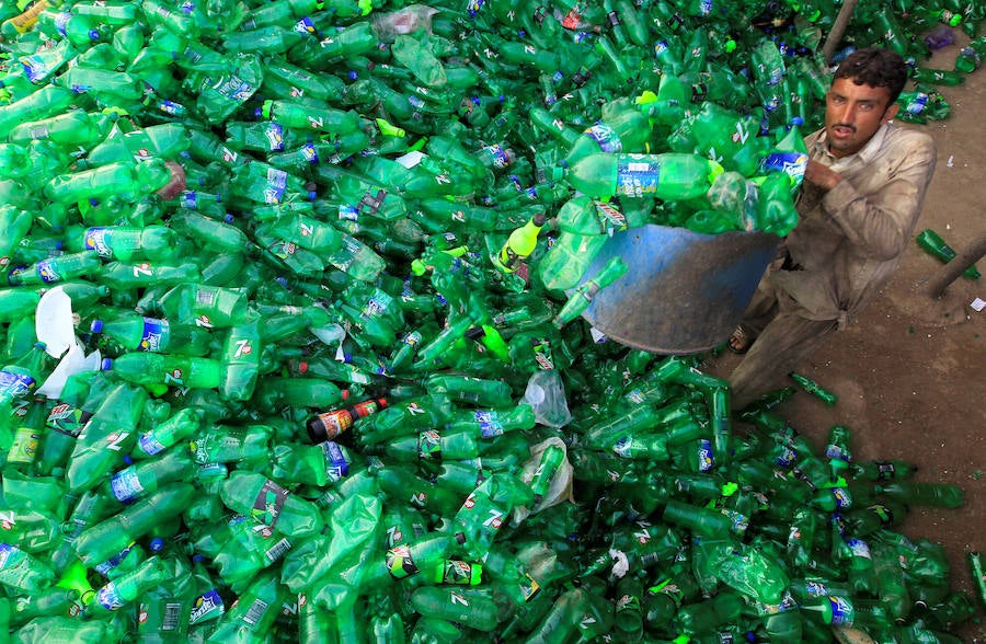 Operarios se abren paso entre montañas de botellas en una de las plantas de reciclaje de la capital de Pakistán