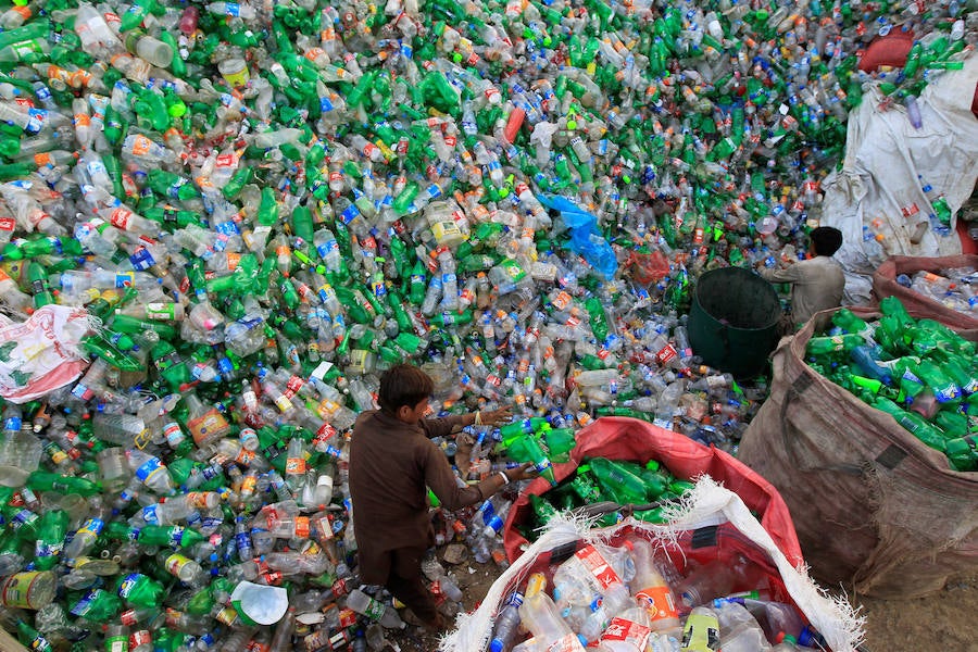 Operarios se abren paso entre montañas de botellas en una de las plantas de reciclaje de la capital de Pakistán