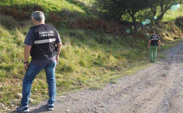 Dos agentes de la Guardia Civil buscan pistas en la zona de Guriezo donde se halló el cadáver de la mujer asesinada. 