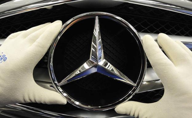 Un trabajador monta la icónica estrella de la firma alemana en la parrilla del radiador de un Mercedes-Benz Clase E, uno de los modelos afectados.