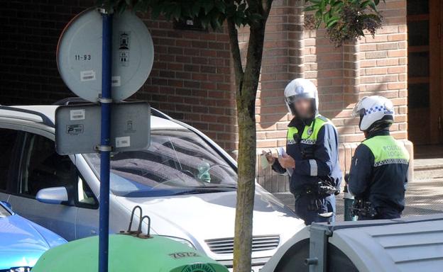 Dos agentes locales colocan una multa a un vehículo mal aparcado. 