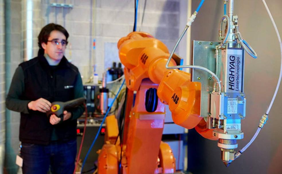 Un operario de empresa manipula un robot.