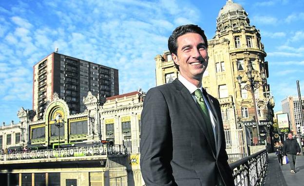 Ochandiano posa sonriente en el puente de El Arenal, con la monumental fachada de la estación de La Concordia al fondo.