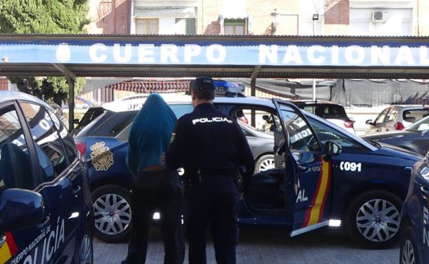 Un policía nacional conduce al supuesto autor del robo.