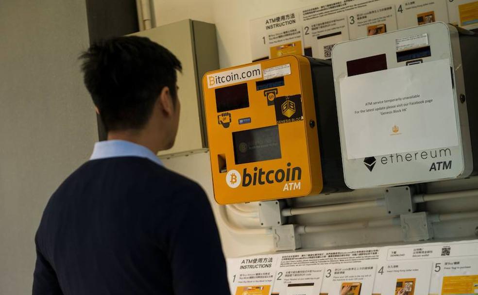 Un hombre observa un cajero de bitcoin en Hong Kong.