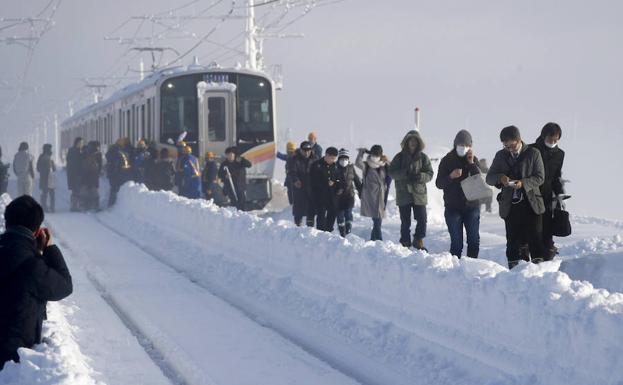 Varios pasajeros abandonan el tren detenido. 