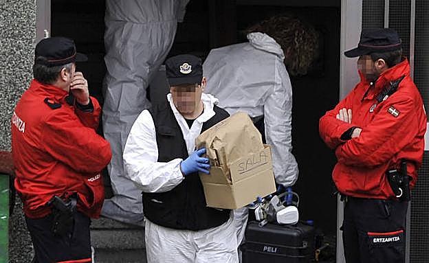 Agentes de la Policía Científica de la Ertzaintza extraen ayer una caja con evidencias del domicilio donde fue asesinada una pareja, en Otxarkoaga.