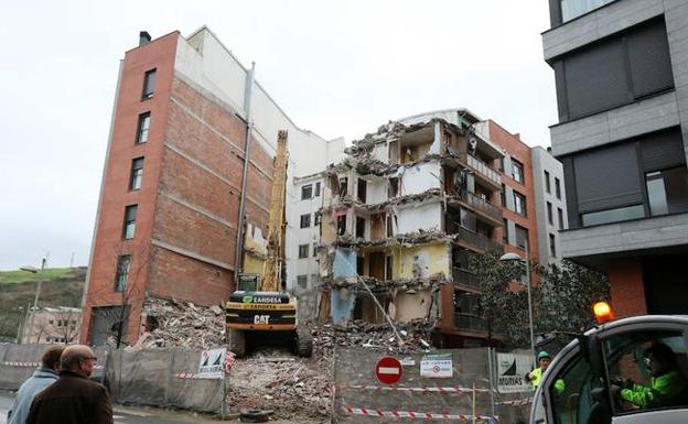 Dos vecinos observan los trabajos de demolición del primero de los edificios afectados por daños estructurales en Erandio. 