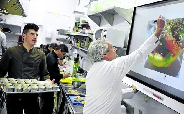 Imagen principal - 1. Fernando Canales interactúa con la pantalla donde se condensa el cerebro del Atelier y la Despensa. Además de gestionar las comandas y el servicio, los nuevos platos podrán crearse aquí aunque los cocineros no se encuentren en el local. 2 y 3.Mikel Población, llamado a asumir un papel protagonista en la casa, ultima una lasaña de anchoas, una de las señas de identidad de Etxanobe y presente en los menús. A la derecha, ajoblanco de trufa con espárragos y gambas y (debajo), pulpo asado y espuma de patata y pimentón. Son platos de la nueva carta.