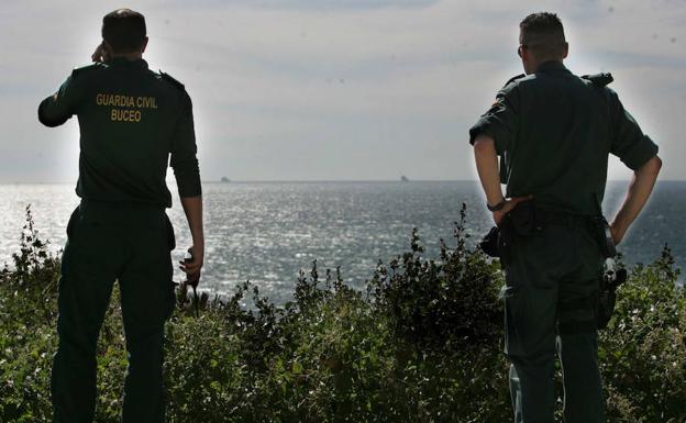 Imagen principal - Arriba, dos guardias civiles vigilan el Estrecho desde la costa gaditana. Abajo a la izquierda, zona en la que había un radar oculto. Abajo a la derecha, salida que utilizaban los narcotraficantes desde la playa.