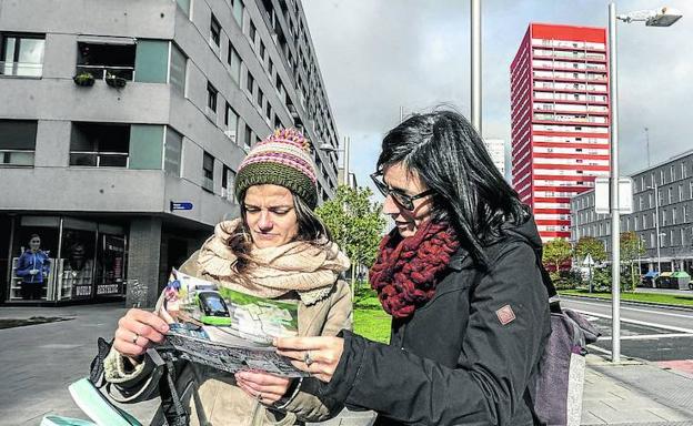 Dos vecinas revisan uno de los folletos del tranvía en el Bulevar de Salburua, por donde se proyecta que circule el metro ligero. 