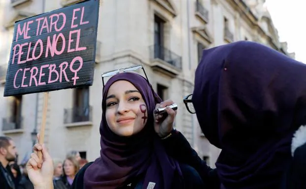 Dos mujeres se pintan el síbolo femenino en la cara momentos antes de iniciarse la manifestación que con el lema "si nosotras paramos, se para el mundo" y que ha reunido a miles de personas en el centro de Valencia. 