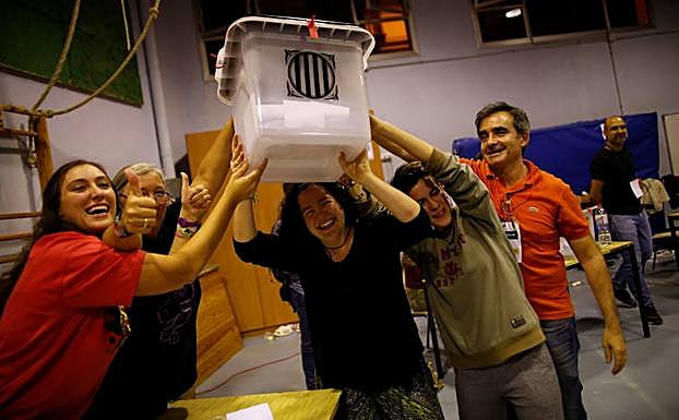 Voluntarios alzan una urna del referéndum catalán.