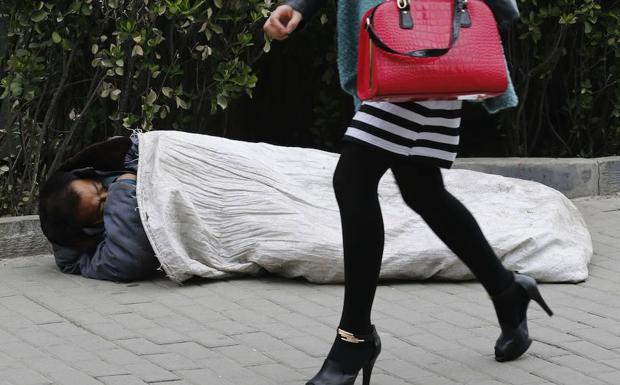 Una mujer pasa por al lado de una persona que duerme en la calle.