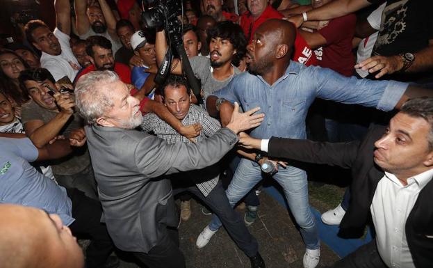 Lula da Silva (c) abandona la sede del Sindicato de los Metalúrgicos de Sao Bernardo do Campo (Brasil) en medio de un tumulto para entregarse a las autoridades.