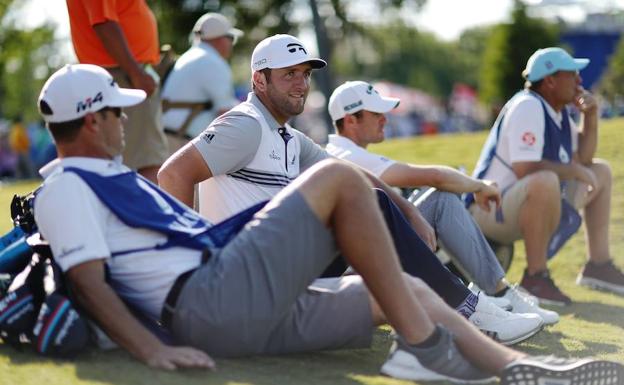 Jon Rahm y Wesley Bryan, sentado a su izquierda, aguardan junto a sus caddies el momento de entrar en acción.