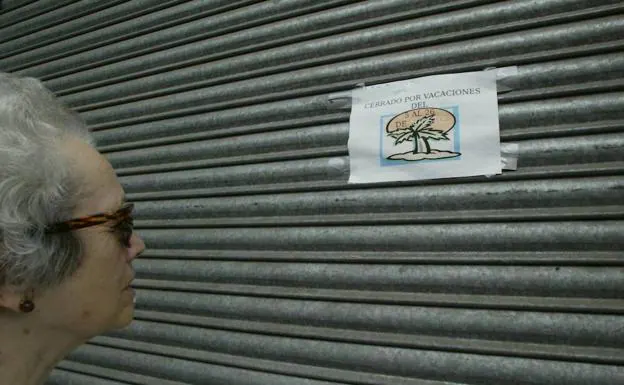 Una mujer observa un cartel de 'cerrado por vacaciones'.