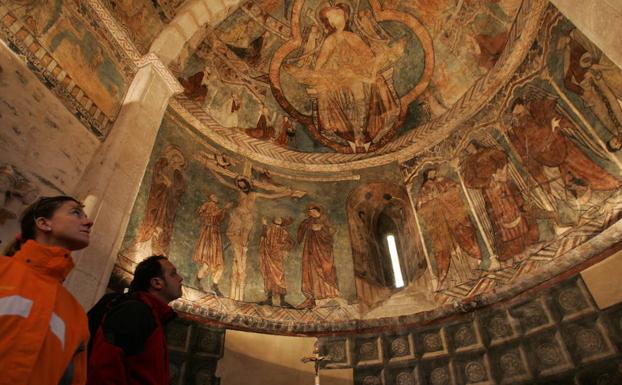 Imagen principal - Dos visitantes observan el techo polícromo de Gazeo. Abajo a la izquierda, ventana con dibujos en Arbulo. Abajo a la derecha, capiteles de la iglesia de Añua.