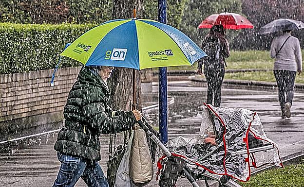 El temporal de lluvia pilla a estos viandantes en la calle Honduras.