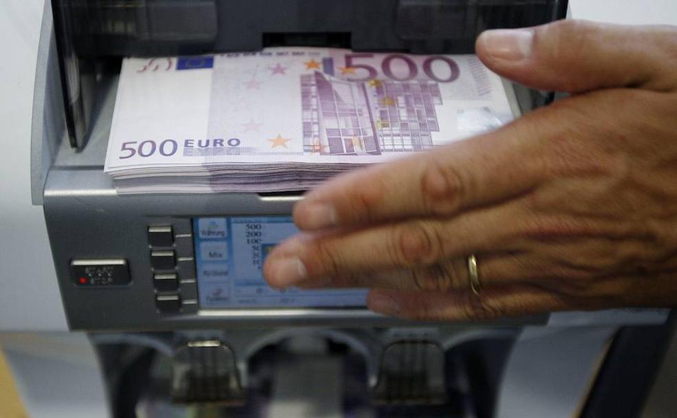 Trabajadora de un banco suiza coloca un fajo de billetes de 500 euros en una máquina contadora.