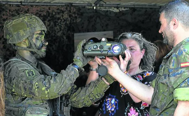 Un soldado muestra a una visitante cómo funciona una cámara de visión nocturna.