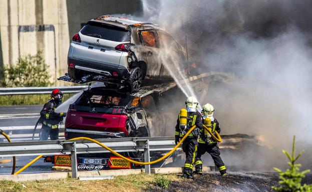 Los bomberos tratan de sofocar las llamas de los turismos. 