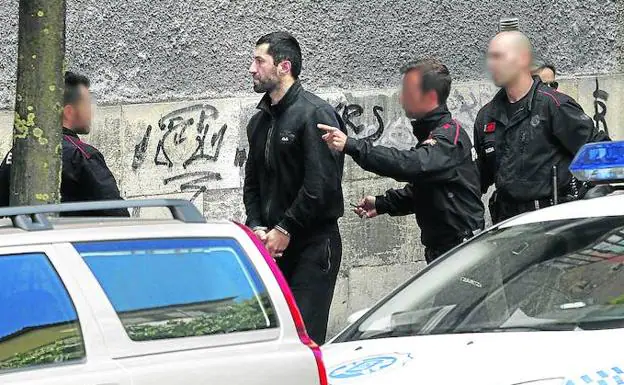 Ertzainas conducen a un ladrón de viviendas, detenido por la Policía Local 24 horas antes, al registro de su piso franco, en el que se halló dinero y joyas de sus golpes. 