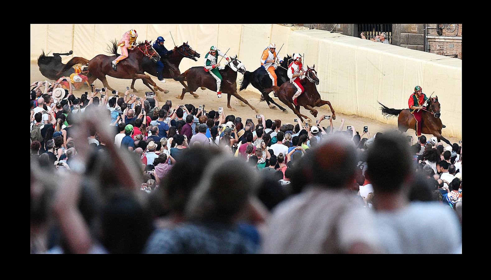 En la Piazza del Campo, en pleno corazón de Siena, en la Toscana, se celebra cada año, en dos ocasiones (las fotografías se tomaron el 2 de julio), la carrera de caballos de origen medieval conocida como «Il Palio.» La ciudad se engalana con estandartes, blasones y guirnaldas para celebrar tres días de alegría durante los cuales, además de participar en las bendiciones de los animales, es posible disfrutar de música y conciertos. En la carrera participan diez caballos, que representan a alguna de las «contradas» o distritos de la ciudad, y han de dar tres vueltas completas a la Piazza del Campo. El primero en terminarlas, con o sin jinete, será el ganador.