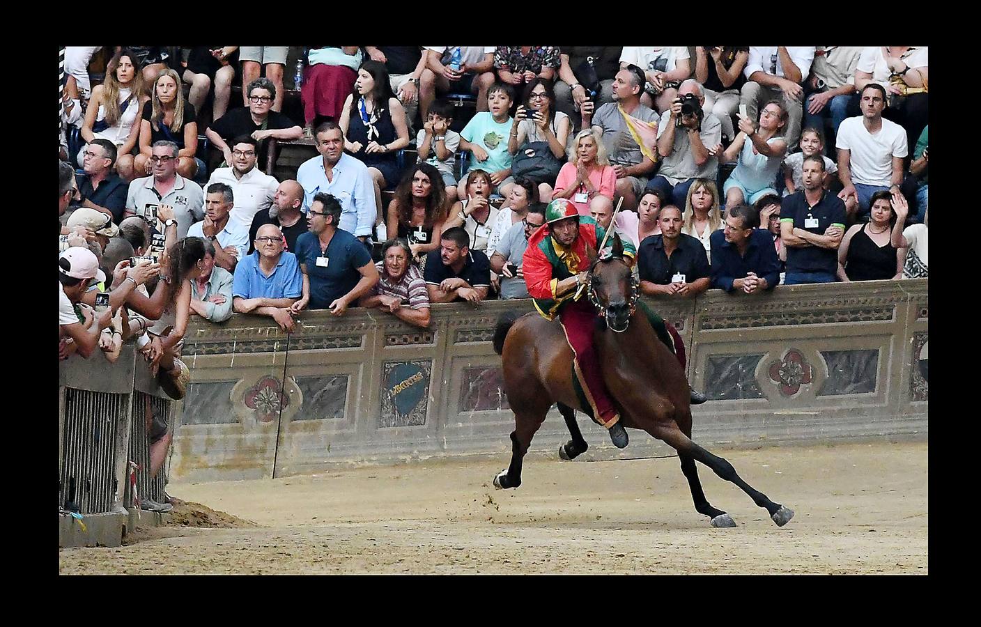 En la Piazza del Campo, en pleno corazón de Siena, en la Toscana, se celebra cada año, en dos ocasiones (las fotografías se tomaron el 2 de julio), la carrera de caballos de origen medieval conocida como «Il Palio.» La ciudad se engalana con estandartes, blasones y guirnaldas para celebrar tres días de alegría durante los cuales, además de participar en las bendiciones de los animales, es posible disfrutar de música y conciertos. En la carrera participan diez caballos, que representan a alguna de las «contradas» o distritos de la ciudad, y han de dar tres vueltas completas a la Piazza del Campo. El primero en terminarlas, con o sin jinete, será el ganador.