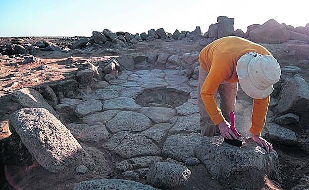 Un arqueólogo trabaja en la zona del hogar -el agujero a sus espaldas- en el yacimiento jordano de Shutbayqa 1.