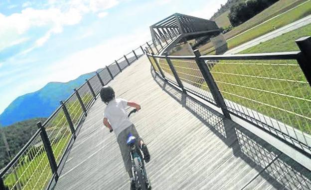 Un niño atraviesa en bici una pasarela del Vasco Navarro en Antoñana. 