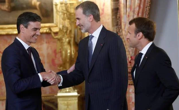El rey Felipe VI, junto al presidente de Francia, Emmanuel Macron (d), saluda al presidente del Gobierno español, Pedro Sánchez (i), durante la reunión que han mantenido esta noche en el Palacio Real de Madrid.