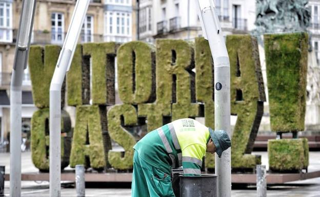 Un operario limpia una papelera de la plaza de la Virgen Blanca, en Vitoria.