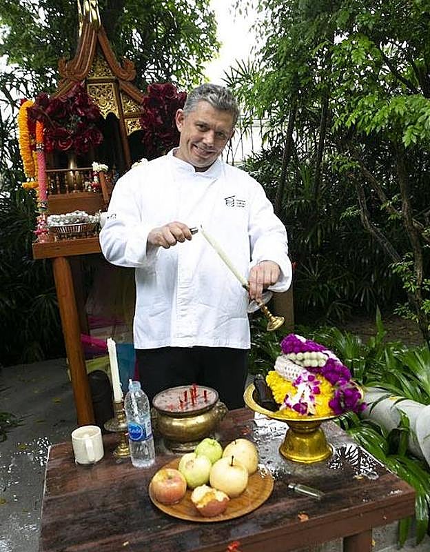 Álvaro Garrido enciende una vela en un jardín de Bangkok.