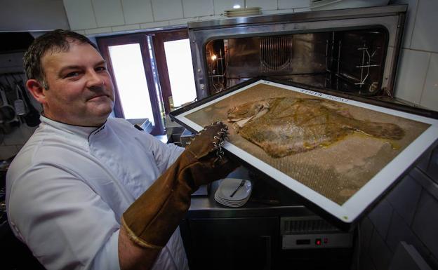 Mikel Bengoa saca un pescado del horno de su local en Meñaka.