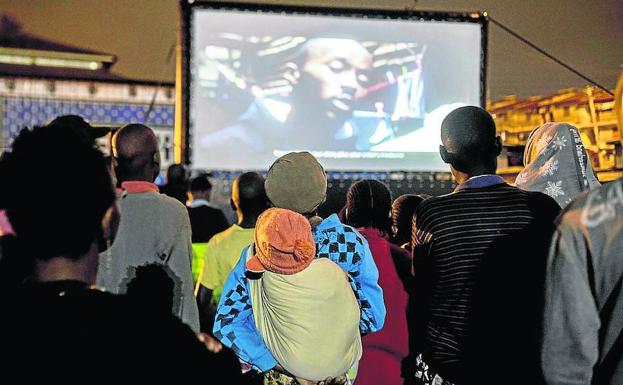 Adultos y niños disfrutan de una noche de cine en el suburbio de Kibera.
