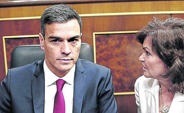 Sánchez, con la irritación y el desánimo reflejados en su semblante, atiende a la vicepresidenta Carmen Calvo ayer en el Congreso. 
