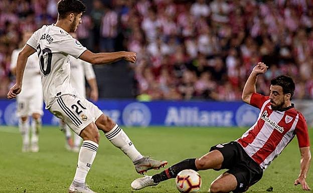 El centrocampista del Athletic de Bilbao, Beñat Etxebarria, disputa un balón con el delantero del Real Madrid, Marco Asensio.