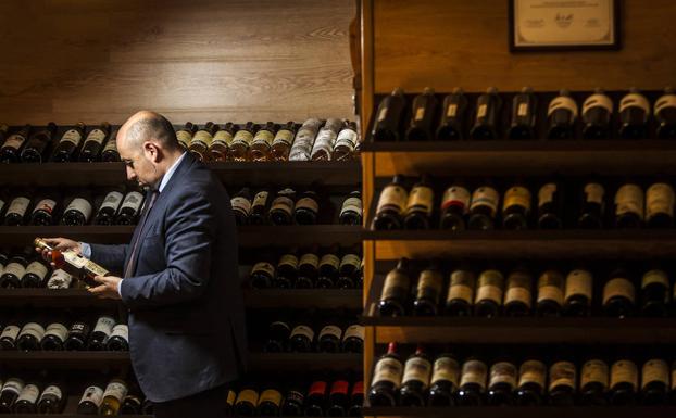 Carlos Echapresto examina una de las botellas que tiene expuestas en la bodega situada junto al comedor principal.